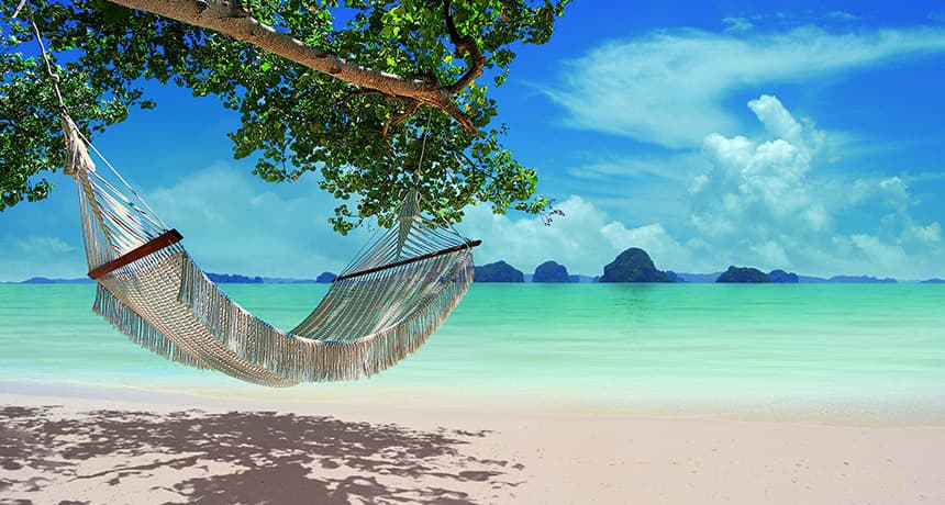 Relaxing hammock on pristine Thai beach with turquoise water and limestone islands